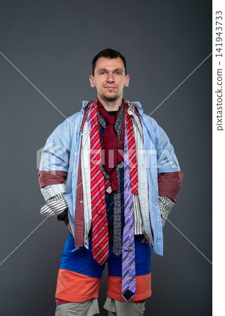 Portrait of a man with a messy haircut standing against a gray wall Portrait of a man with a messy haircut standing against a gray wall 141943733