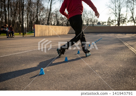 Young man in a red hoodie practicing freestyle rollerblading tricks Young man in a red hoodie practicing freestyle rollerblading tricks 141943791