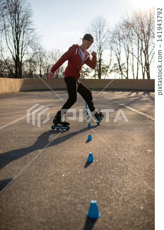 Young man in a red hoodie practicing freestyle rollerblading tricks Young man in a red hoodie practicing freestyle rollerblading tricks 141943792