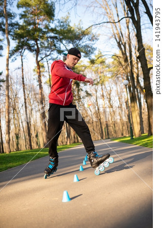 A skater rolling around blue cones on a path A skater rolling around blue cones on a path 141943795