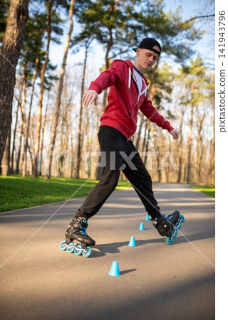 Lower body view of a skater rolling around blue cones on a path Lower body view of a skater rolling around blue cones on a path 141943796