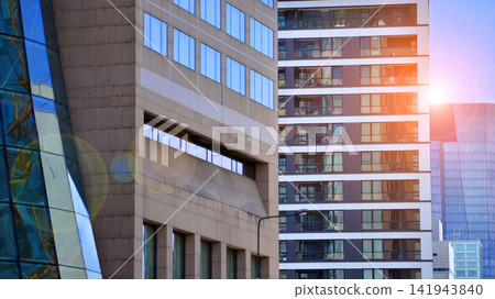View of an new modern office building a with a glass facade standing next to modern apartment building. View of an new modern office building a with a glass facade standing next to modern apartment building. 141943840
