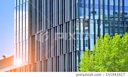 City life, urban landscape and ecology. Modern office complex with glass facades and smooth lines against backdrop of green trees, concept of modern architecture. Organically building into nature. City life, urban landscape and ecology. Modern office complex with glass facades and smooth lines against backdrop of green trees, concept of modern architecture. Organically building into nature. 141943917
