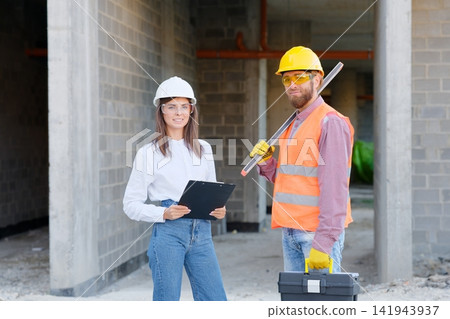 Construction workers discussing blueprint at building site Construction workers discussing blueprint at building site 141943937