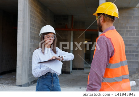 Engineers discussing construction plan on site wearing protective gear 141943942