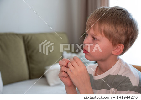 Boy holds fresh blueberries in his hands while sitting at home and looking thoughtfully away. Childhood, healthy snack, nutrition, mindful eating, wellbeing, food choice, family lifestyle, healthy Boy holds fresh blueberries in his hands while sitting at home and looking thoughtfully away. Childhood, healthy snack, nutrition, mindful eating, wellbeing, food choice, family lifestyle, healthy 141944270