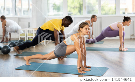 Young female teacher working out surya namaskar with multinational students group Young female teacher working out surya namaskar with multinational students group 141944641