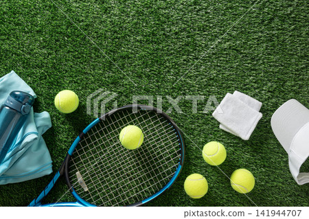Tennis gear with racket and balls on green grass top view Tennis gear with racket and balls on green grass top view 141944707