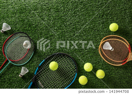 Tennis and badminton rackets with balls on green grass 141944708
