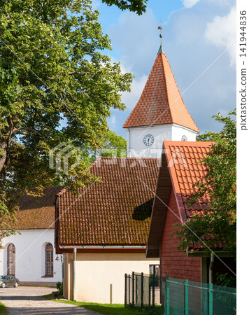 Historic Church Clock Tower Rising Above Traditional Rooftops and Green Trees in Talsi Latvia Historic Church Clock Tower Rising Above Traditional Rooftops and Green Trees in Talsi Latvia 141944836