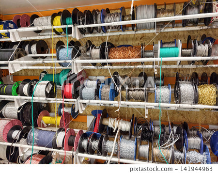 Heavy duty ropes cables and chains neatly stored in loops and spools within a building supply store ready for use in lifting and securing operations Heavy duty ropes cables and chains neatly stored in loops and spools within a building supply store ready for use in lifting and securing operations 141944963