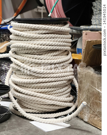 Heavy coil of white rope displayed in a building supply setting highlighting durable twisted fiber designed for lifting fastening and general utility work in construction industry Heavy coil of white rope displayed in a building supply setting highlighting durable twisted fiber designed for lifting fastening and general utility work in construction industry 141945014