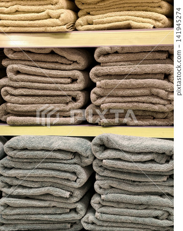 Assorted bright towels arranged on supermarket shelves highlighting folded cotton textile products in different colors prepared for retail shopping environment Assorted bright towels arranged on supermarket shelves highlighting folded cotton textile products in different colors prepared for retail shopping environment 141945274