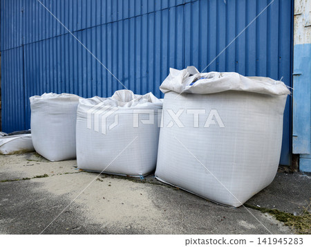 Large white sandbags placed near the warehouse gates for protection and safety Large white sandbags placed near the warehouse gates for protection and safety 141945283