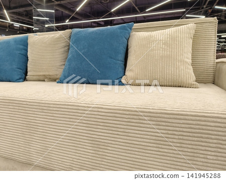 A soft sofa with beige and blue cushions, ideal for your living room, for sale in a furniture store A soft sofa with beige and blue cushions, ideal for your living room, for sale in a furniture store 141945288