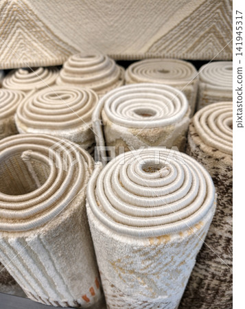 Comfortable textured carpets rolled into large rolls displayed in a superstore with decorative materials and elegant patterns Comfortable textured carpets rolled into large rolls displayed in a superstore with decorative materials and elegant patterns 141945317