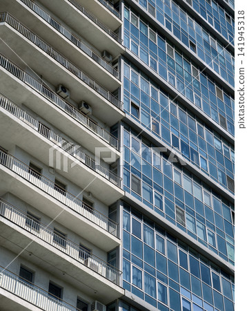 High blue apartment tower with clean facade surfaces and large residential glass windows 141945318