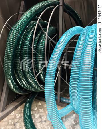 Thick blue and green corrugated plastic hoses are displayed on hardware store racks for plumbing and construction projects Thick blue and green corrugated plastic hoses are displayed on hardware store racks for plumbing and construction projects 141945415