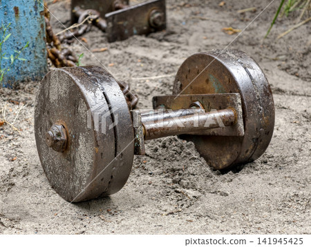 Large iron dumbbell placed on the ground of an outdoor gym area for strength workout bodybuilding and weightlifting training Large iron dumbbell placed on the ground of an outdoor gym area for strength workout bodybuilding and weightlifting training 141945425