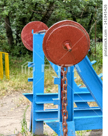 Old barbell with red iron plates standing outdoors as classic strength equipment for squat workout shoulder exercise and muscle training Old barbell with red iron plates standing outdoors as classic strength equipment for squat workout shoulder exercise and muscle training 141945426