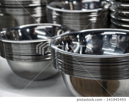 Shiny stacked stainless steel bowls in supermarket display shelving, representing durable kitchenware with polished metal surfaces for modern home cooking 141945493