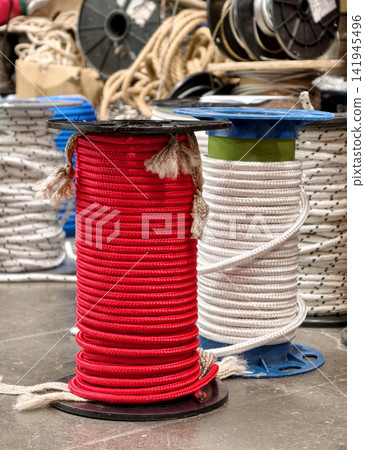 Red and white rope bundles placed in large coils on the store floor in a building supply area presenting strong fiber products for lifting securing and transport applications Red and white rope bundles placed in large coils on the store floor in a building supply area presenting strong fiber products for lifting securing and transport applications 141945496