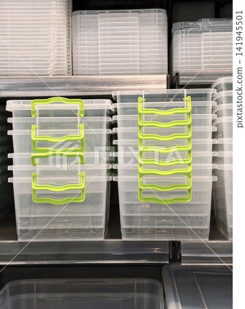 Plastic containers with green handles in large and small sizes neatly arranged on retail shelves with lids stacked separately nearby for efficient storage concept Plastic containers with green handles in large and small sizes neatly arranged on retail shelves with lids stacked separately nearby for efficient storage concept 141945501