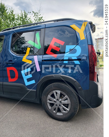 Car with eye catching colorful DELIVERY lettering parked along a residential street creating a clean visual representation of urban transportation and delivery activity Car with eye catching colorful DELIVERY lettering parked along a residential street creating a clean visual representation of urban transportation and delivery activity 141945519