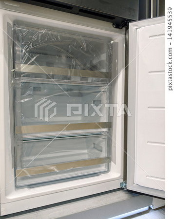 Sleek modern fridge with open freezer door, perfect for stylish kitchens, for sale in a home appliance superstore Sleek modern fridge with open freezer door, perfect for stylish kitchens, for sale in a home appliance superstore 141945539