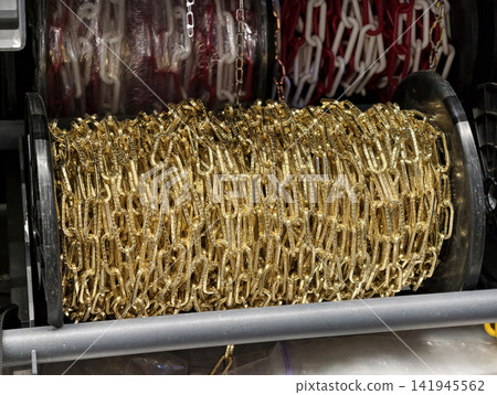 Golden tone steel chain coiled on spools in a building supply supermarket highlighting stylish appearance combined with practical strength Golden tone steel chain coiled on spools in a building supply supermarket highlighting stylish appearance combined with practical strength 141945562