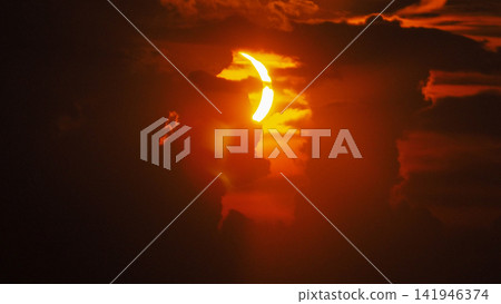Solar Eclipse, Red Sky and Dramatic Clouds at Sunset Solar Eclipse, Red Sky and Dramatic Clouds at Sunset 141946374