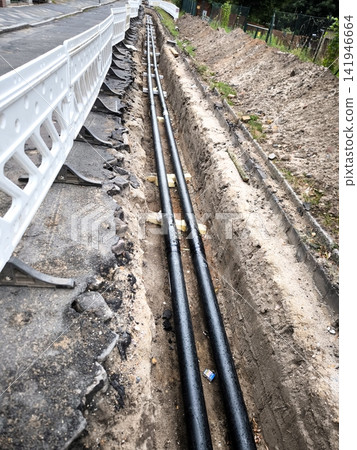 Laying underground utilities and cables in trenches along the fence line. Laying underground utilities and cables in trenches along the fence line. 141946664