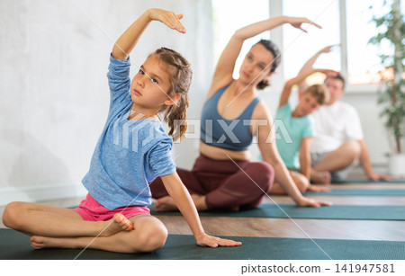 Mother and family performing yoga exercises at yoga studio, family health concept Mother and family performing yoga exercises at yoga studio, family health concept 141947581