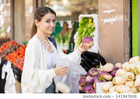 Girl shopper choosing ripe radish at street market Girl shopper choosing ripe radish at street market 141947608
