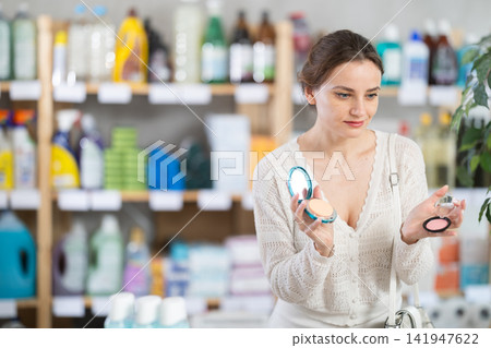 Woman purchases household chemicals in store and chooses eye shadow pallet Woman purchases household chemicals in store and chooses eye shadow pallet 141947622