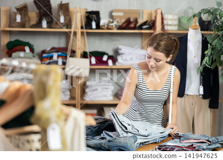 Young woman standing choosing pants in store Young woman standing choosing pants in store 141947625