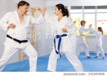 Woman in kimono honing punching techniques during kumite with man Woman in kimono honing punching techniques during kumite with man 141947649