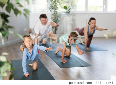 Family with two children doing yoga in studio 141947761