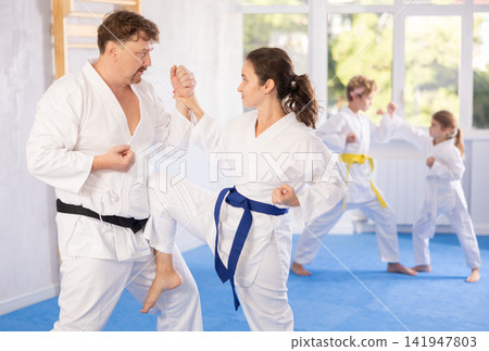 Woman mastering knee strike during sparring with husband at family karate training 141947803