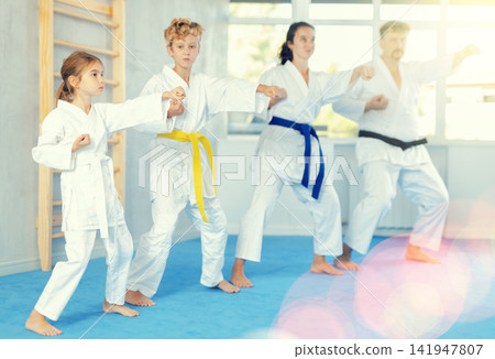 Preteen girl in kimono practicing punches as part of kata during family training Preteen girl in kimono practicing punches as part of kata during family training 141947807