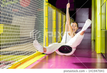 Happy girl goes down zip line at high speed in an amusement park. Storm of emotions and delight Happy girl goes down zip line at high speed in an amusement park. Storm of emotions and delight 141947841
