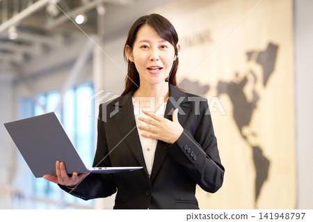 A businesswoman giving a presentation at a seminar, holding a laptop. A businesswoman giving a presentation at a seminar, holding a laptop. 141948797