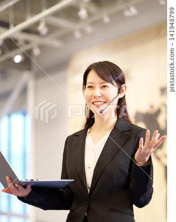 一位女商人正在研討會上演講,她手裡拿著一台筆記型電腦。 一位女商人正在研討會上演講,她手裡拿著一台筆記型電腦。 141948799