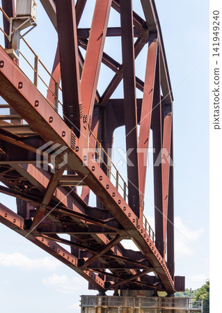 Blue sky and the reddish-brown steel structure of a truss bridge (low-angle shot) Blue sky and the reddish-brown steel structure of a truss bridge (low-angle shot) 141949240