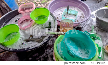 Dirty Plastic Dishes Soaking in Soapy Water Outdoors Dirty Plastic Dishes Soaking in Soapy Water Outdoors 141949404