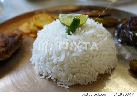 Molded mound of steamed white rice garnished with lime wedge and green chili on a brass plate Molded mound of steamed white rice garnished with lime wedge and green chili on a brass plate 141950347
