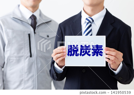 身穿西裝的年輕商人,手持一塊關於脫碳的白板。 身穿西裝的年輕商人,手持一塊關於脫碳的白板。 141950539