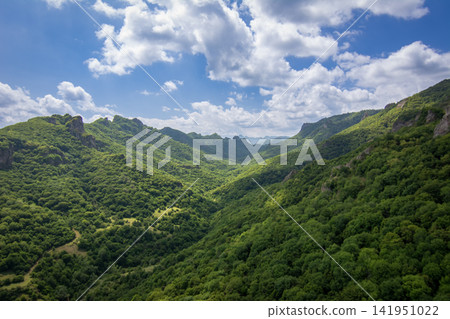 Scenic view of lush green valley with mountains and cloudy sky Scenic view of lush green valley with mountains and cloudy sky 141951022
