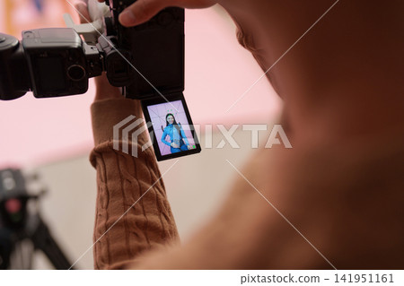 Photographer viewing model on camera LCD screen during studio shoot Photographer viewing model on camera LCD screen during studio shoot 141951161