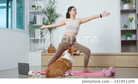 Asian woman practicing yoga at home with corgi dog on mat for fitness Asian woman practicing yoga at home with corgi dog on mat for fitness 141951209